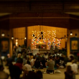 People meditate together inside a dimly lit hall.